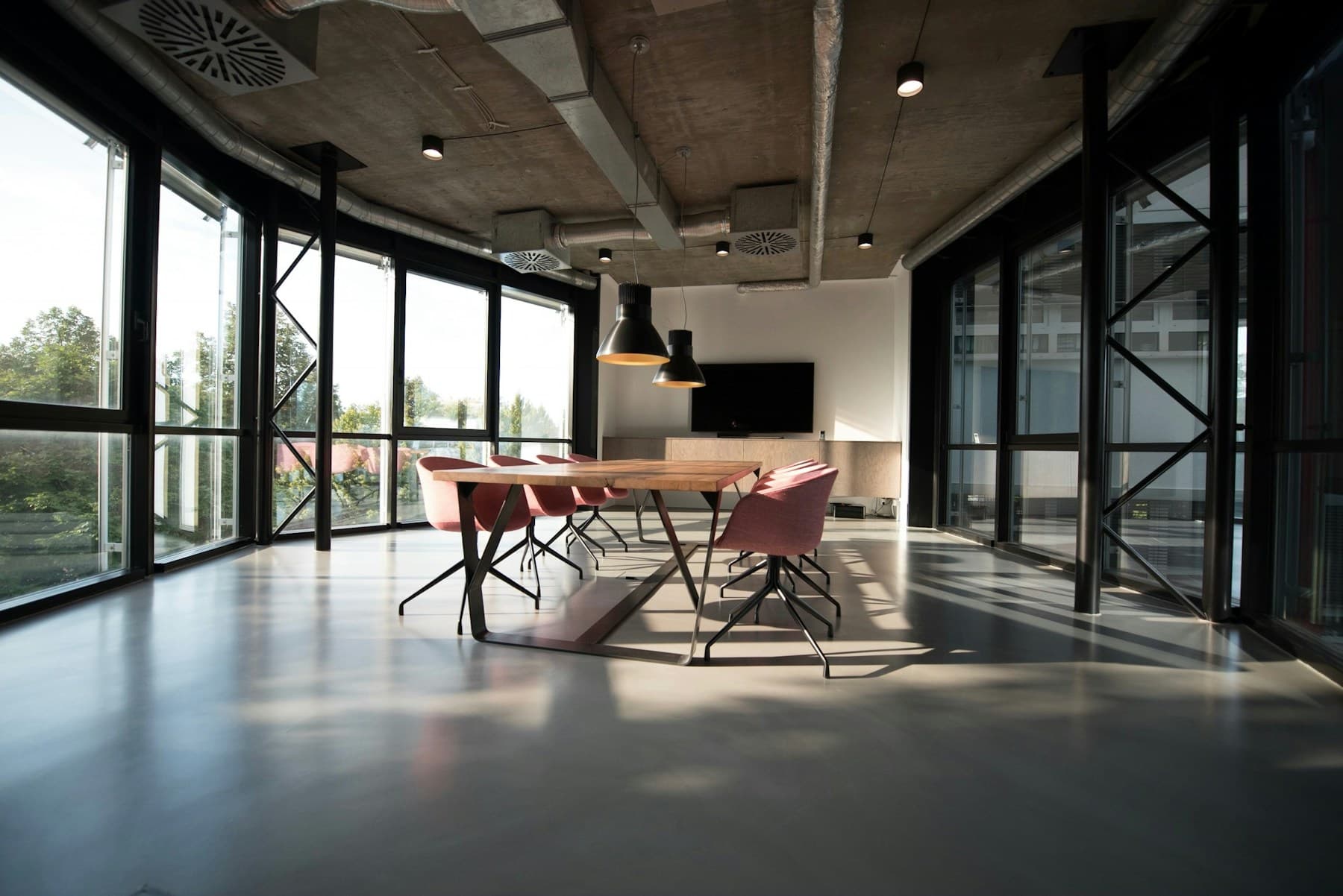 Sunlit office interior with exposed ventilation and a shared meeting table